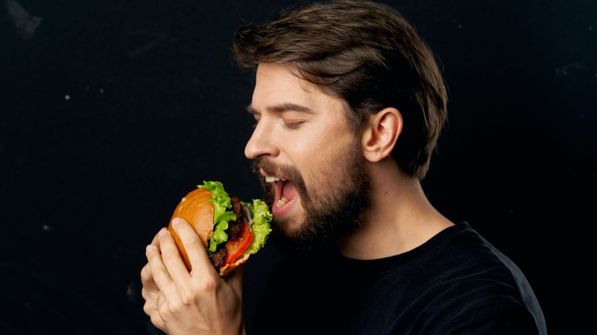 Homem leva hambúrguer à boca - Divulgação