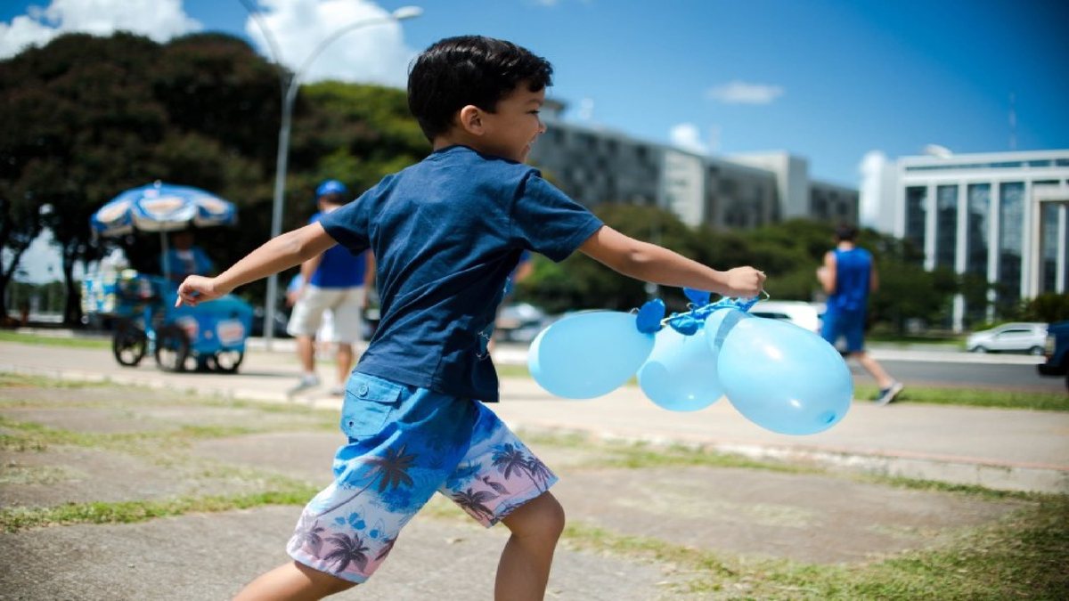 Criança com autismo corre e brinca com bexigas azuis - Divulgação