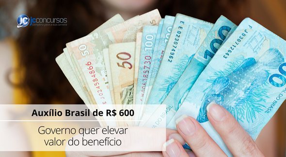 Uma mulher segura notas de dinheiro - Canva - Aumento do Auxílio Brasil