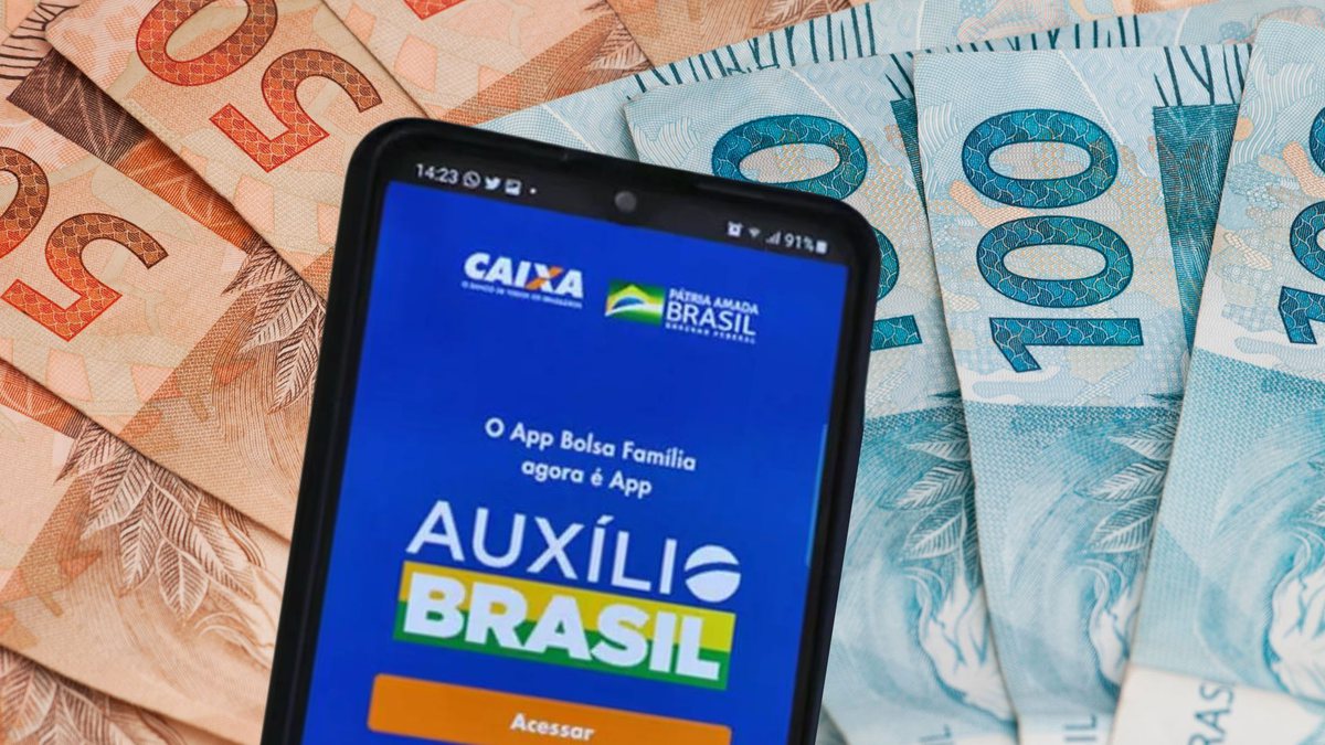 Celular com aplicativo do Auxílio Brasil e notas de cinquenta e cem reais ao fundo - Divulgação