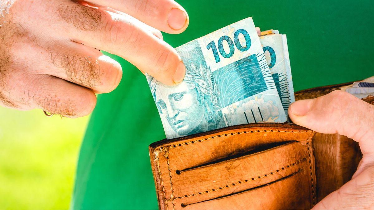 Um homem tira notas de R$ 100 da carteira