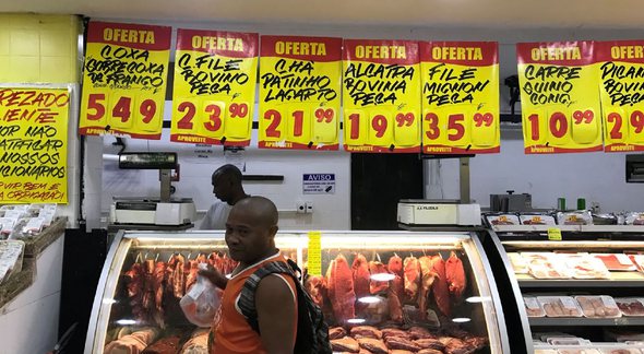 Um homem passa em uma vitrine de carnes no supermercado