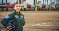 Concurso da Aeronáutica: aviadora da Força Aérea Brasileira posa para foto com aeronaves ao fundo - Agência Força Aérea