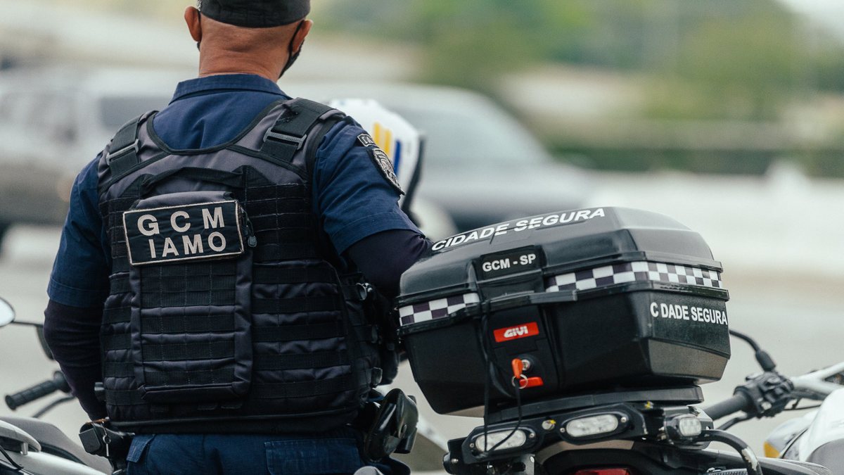 Concurso da GCM SP: agente é visto de costas com uniforme da corporação ao lado de motocicleta