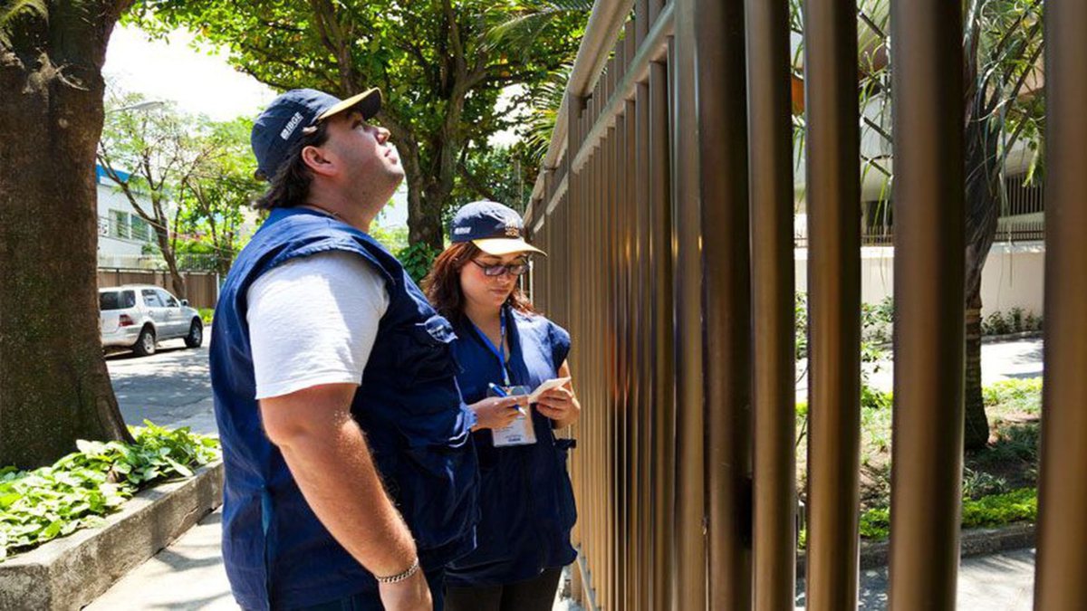 Concurso do IBGE: recenseadores aguardam por atendimento ao lado de portão de residência