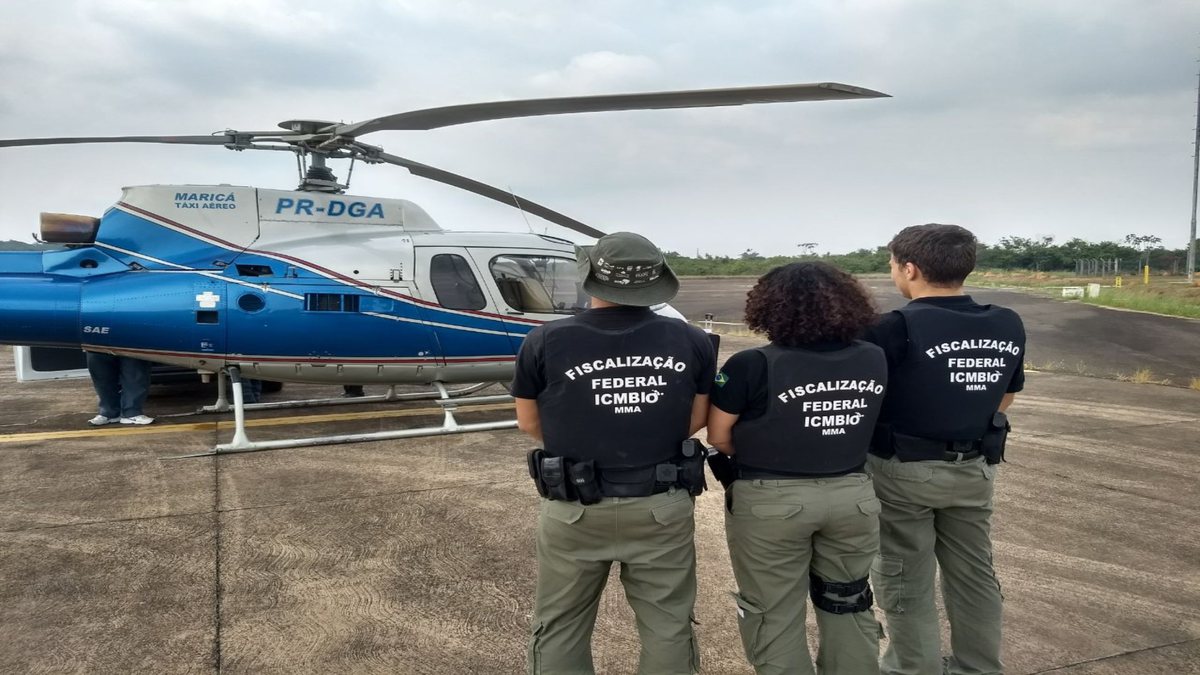 Concurso do ICMBio: servidores vistos de costas ao lado de helicóptero