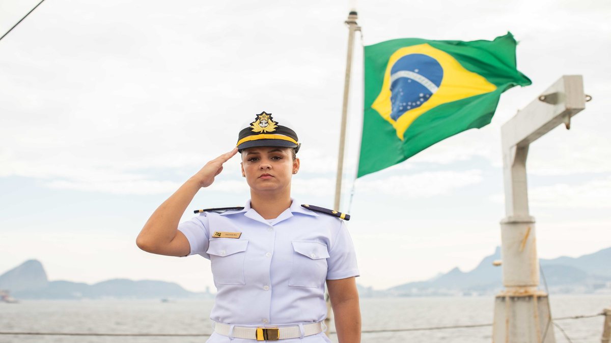 Concurso da Marinha: com bandeira do Brasil ao fundo, militar presta continência