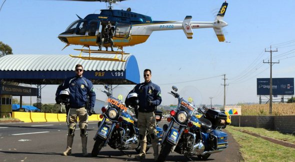 Concurso PRF: com helicóptero ao fundo, dois agentes da corporação posam para foto ao lado de motos - Divulgação
