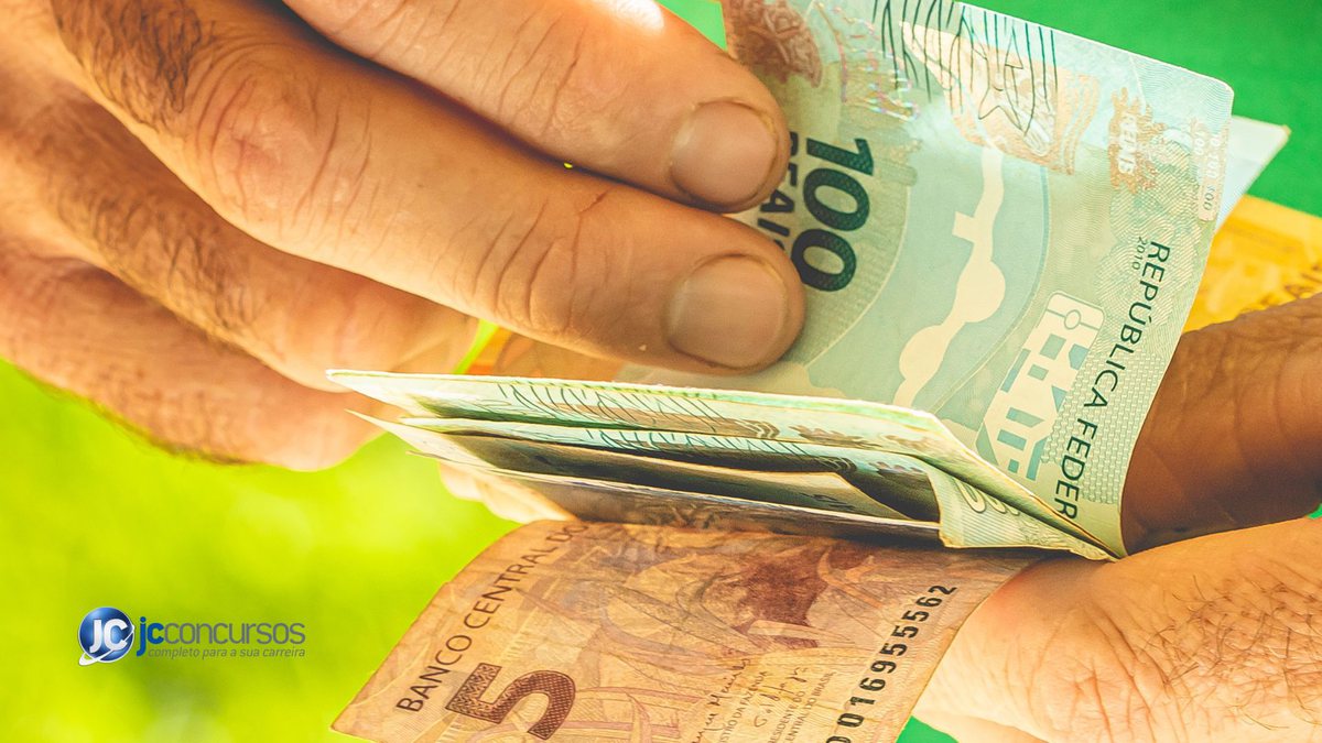 Um homem conta notas de dinheiro - Canva - Saque no valor de R$ 1.000