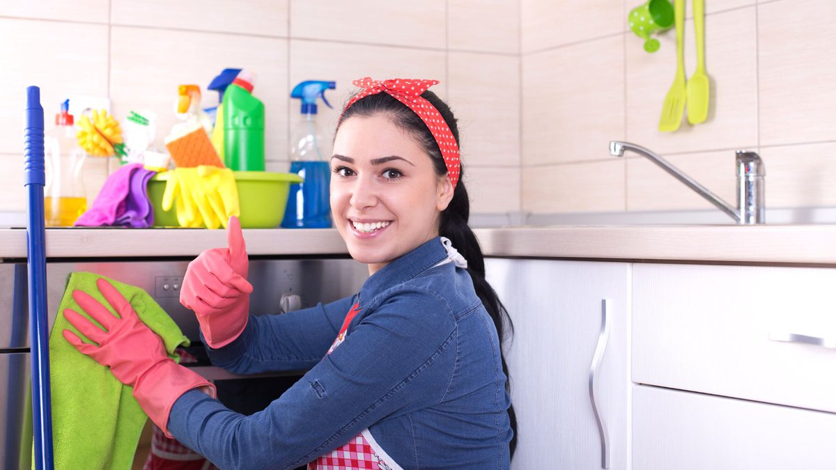Empregada doméstica com luva de limpeza na cor rosa faz sinal de joia com mão e sorri - Divulgação