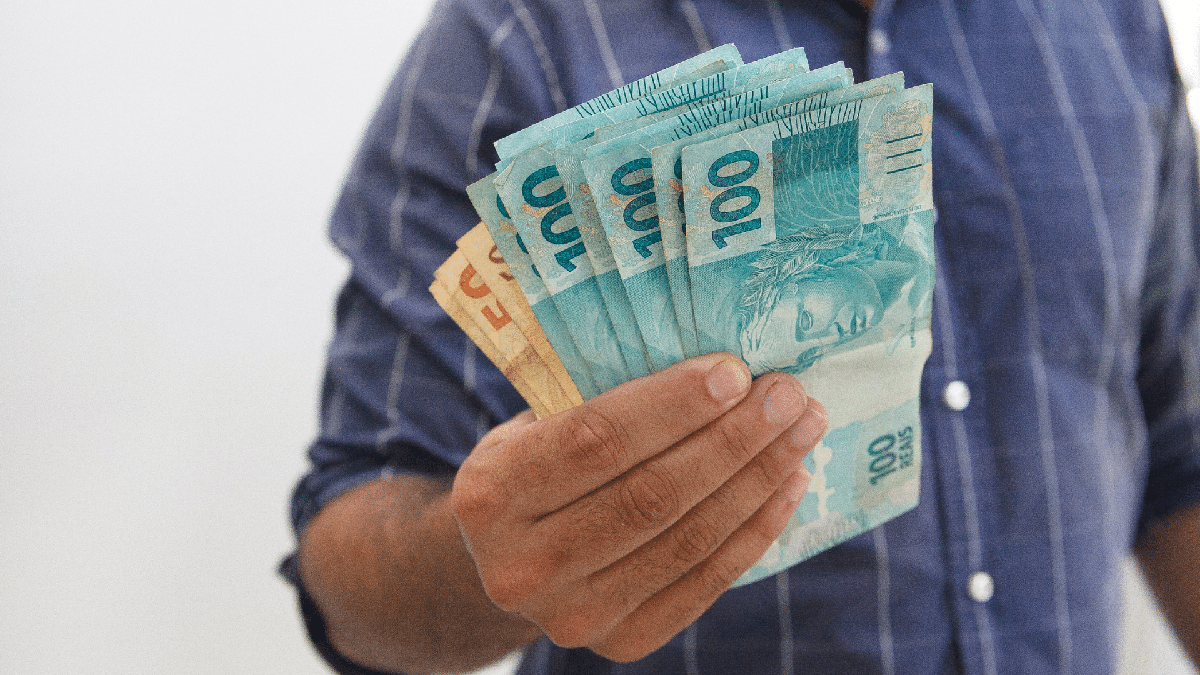 Homem segurando notas de R$ 100 e R$ 50 - Divulgação