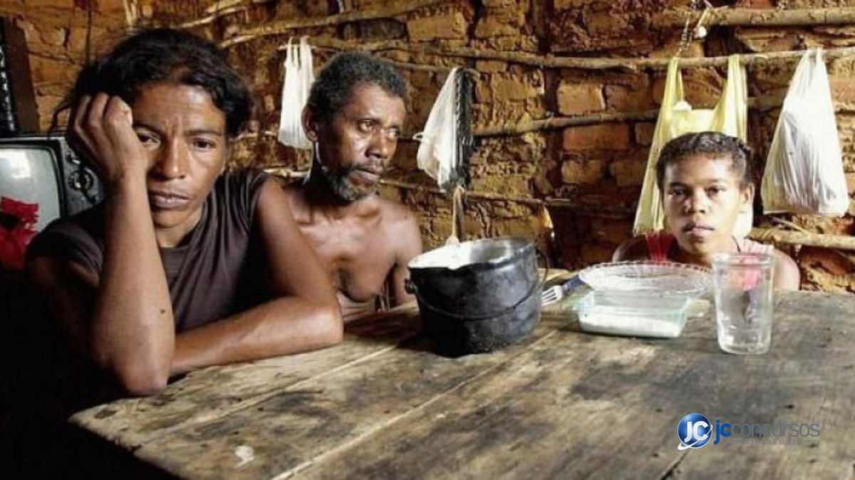Mulher à esquerda, homem no centro e menino à direita, ao redor da mesa em uma casa de barro - Agência Brasil