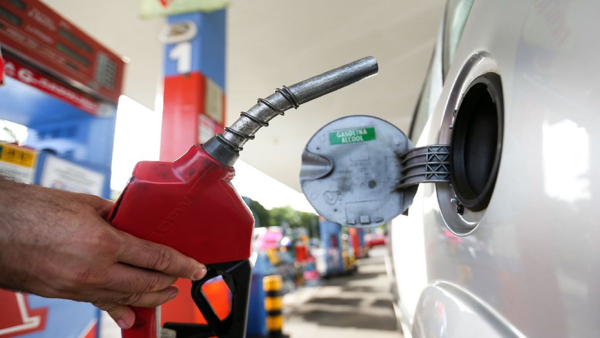 Um homem segura uma bomba de gasolina - Agência Brasil - Petrobras reduz preço da gasolina