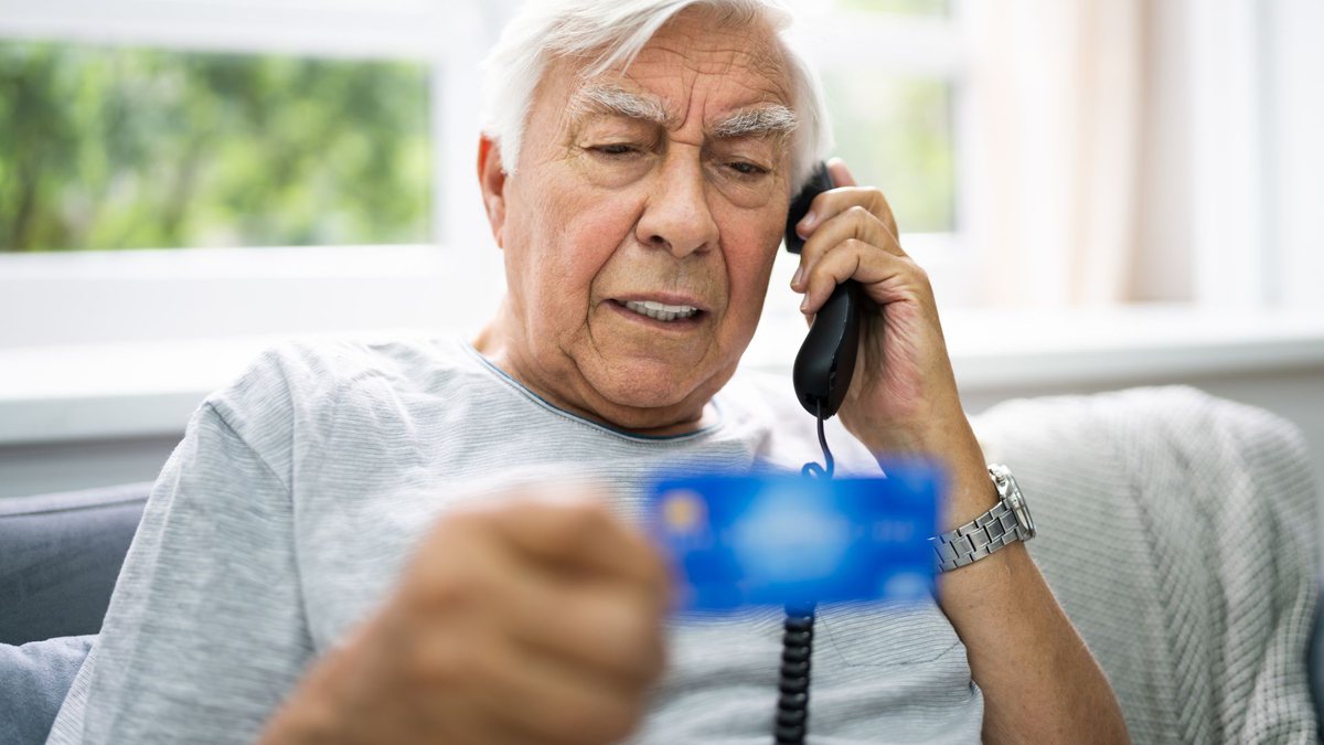 Imagem meramente ilustrativa, um idoso segura o cartão do banco e fala ao telefone - Canva - Golpe no Bradesco