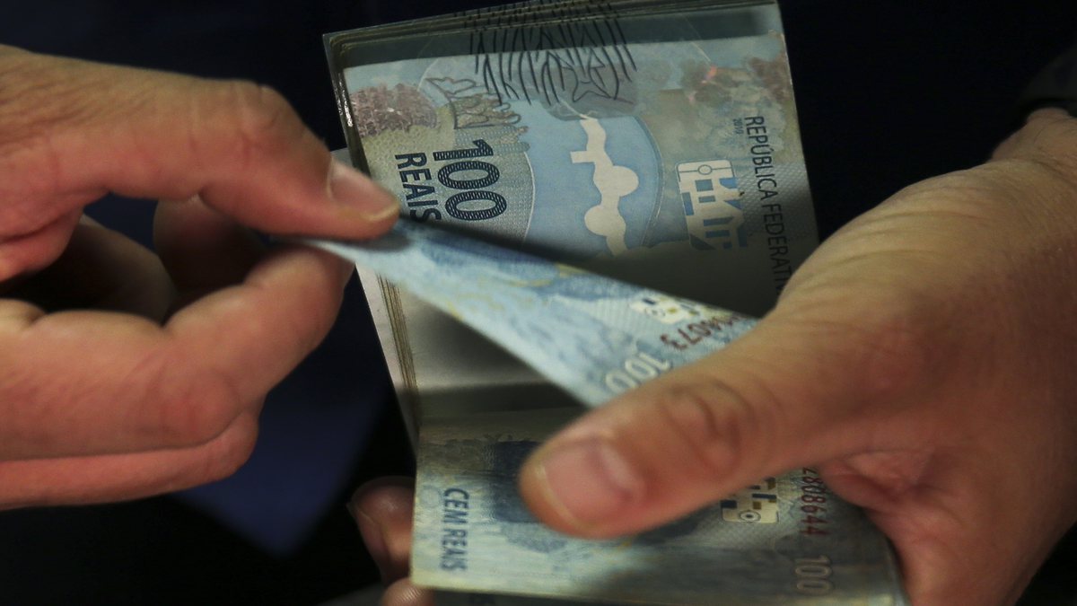 Homem conta notas de dinheiro - Agência Brasil