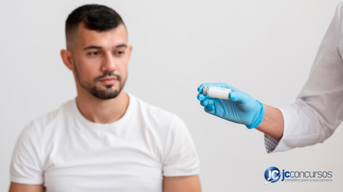 Profissional da saúde segurando ampola para injeção enquanto homem olha para sua mão