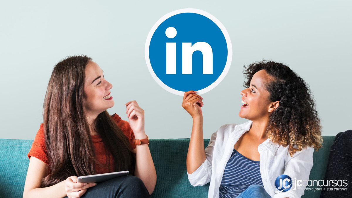 Duas mulheres sentadas em um sofá. Mulher a direita segurando a logomarca do LinkedIn - Freepik
