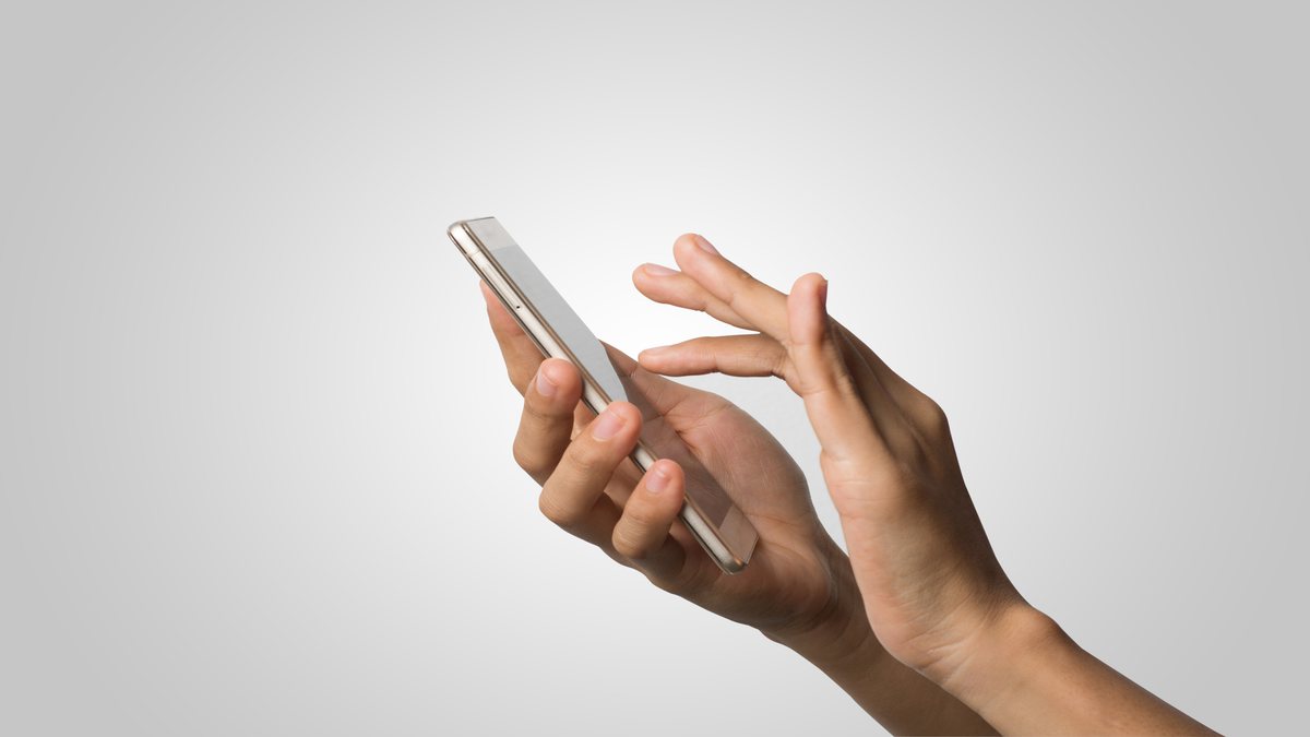 Uma mão digita no celular