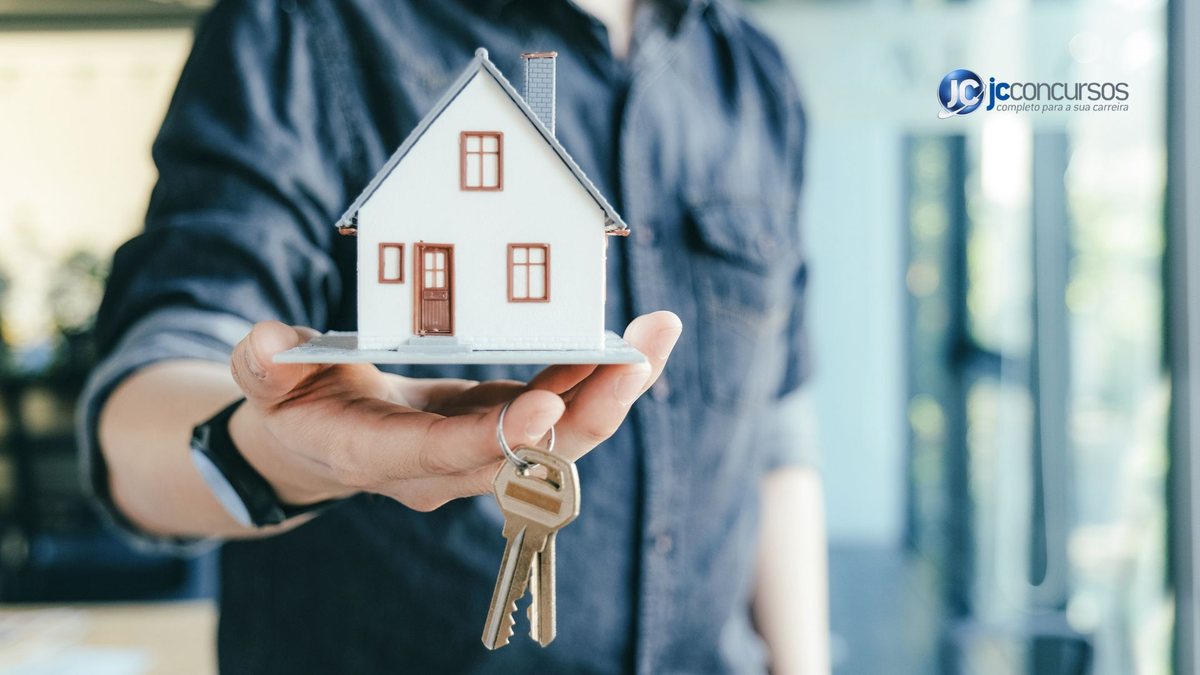 Um homem segura uma chave e uma miniatura de uma casa - Canva - Preço dos aluguéis
