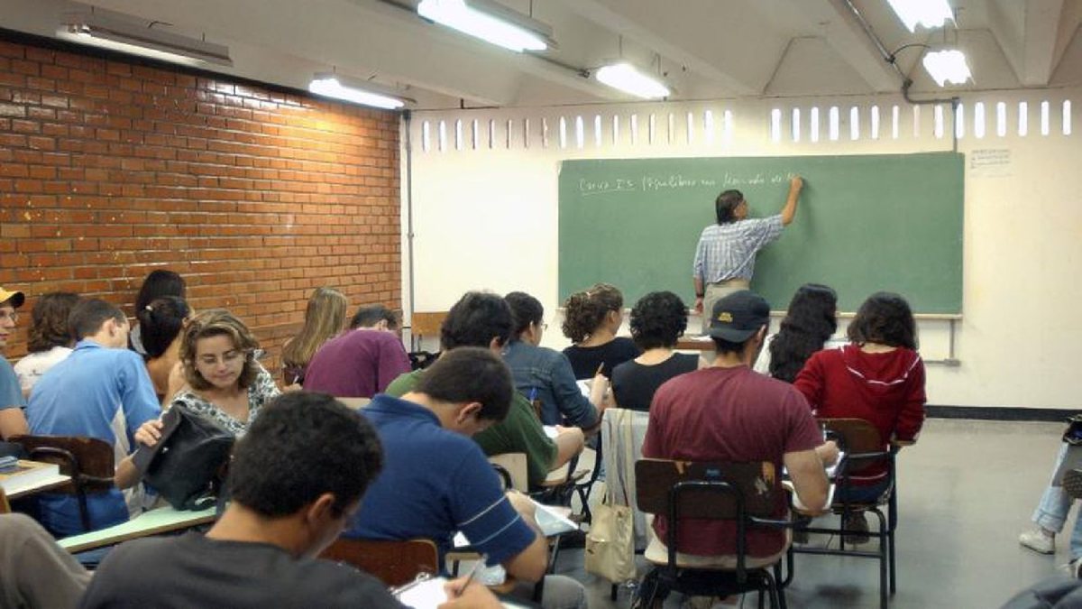 Professor escreve em lousa de sala de aula