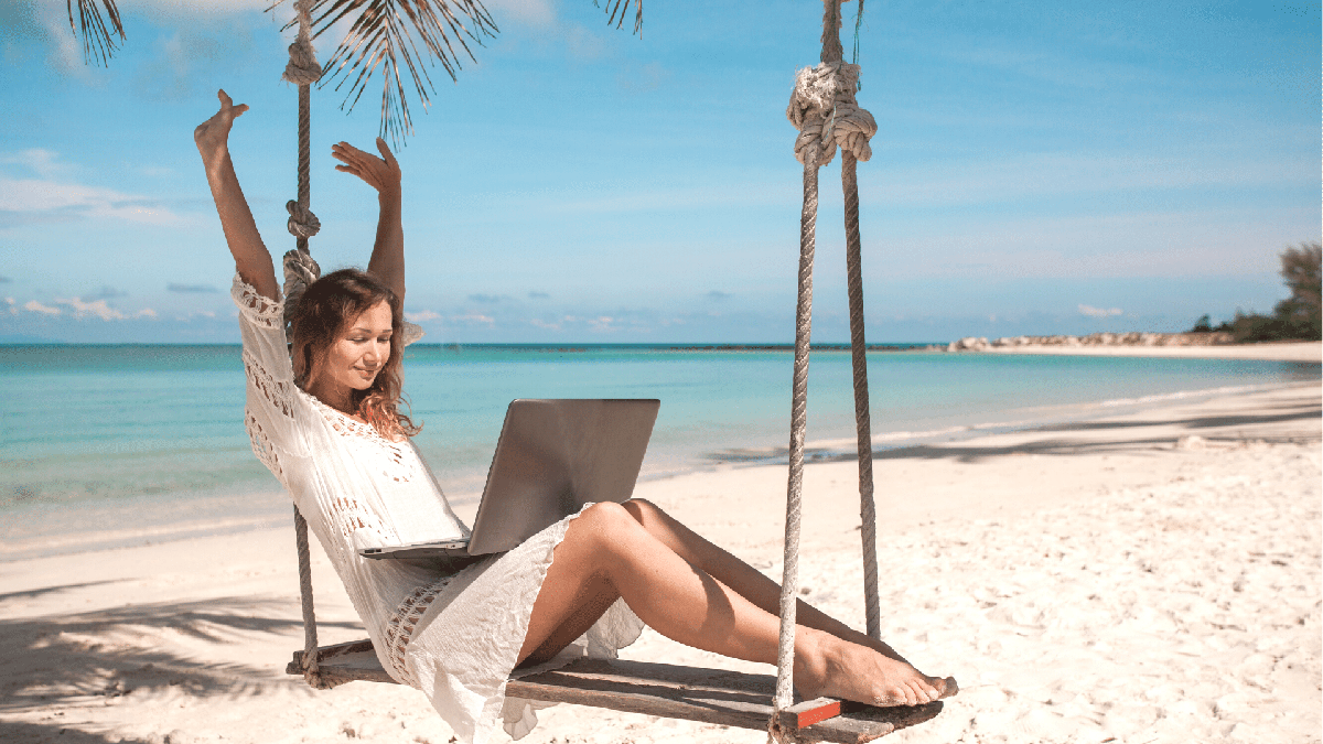 Mulher sentada em balanço em praia paradisíaca - Divulgação
