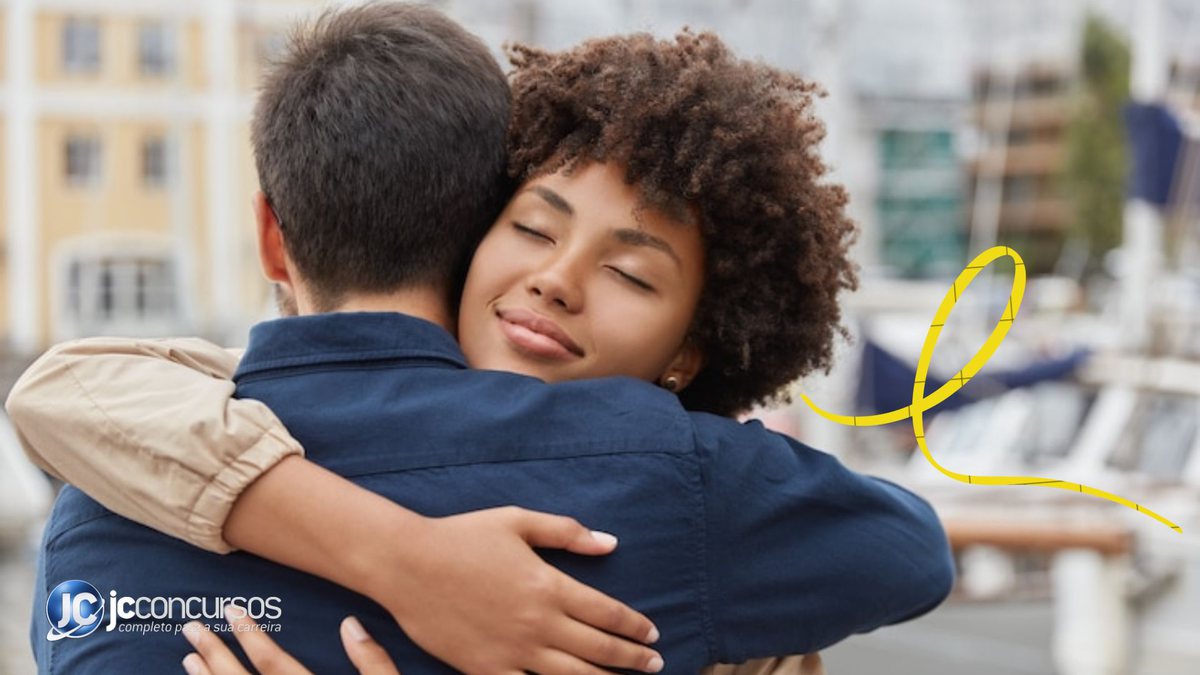Duas pessoas se abraçando e uma fita amarela ao lado