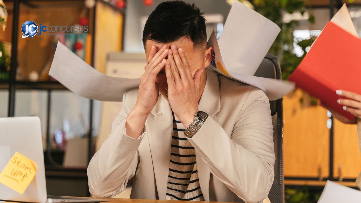 Um homem coloca as mãos no rosto no ambiente de trabalho