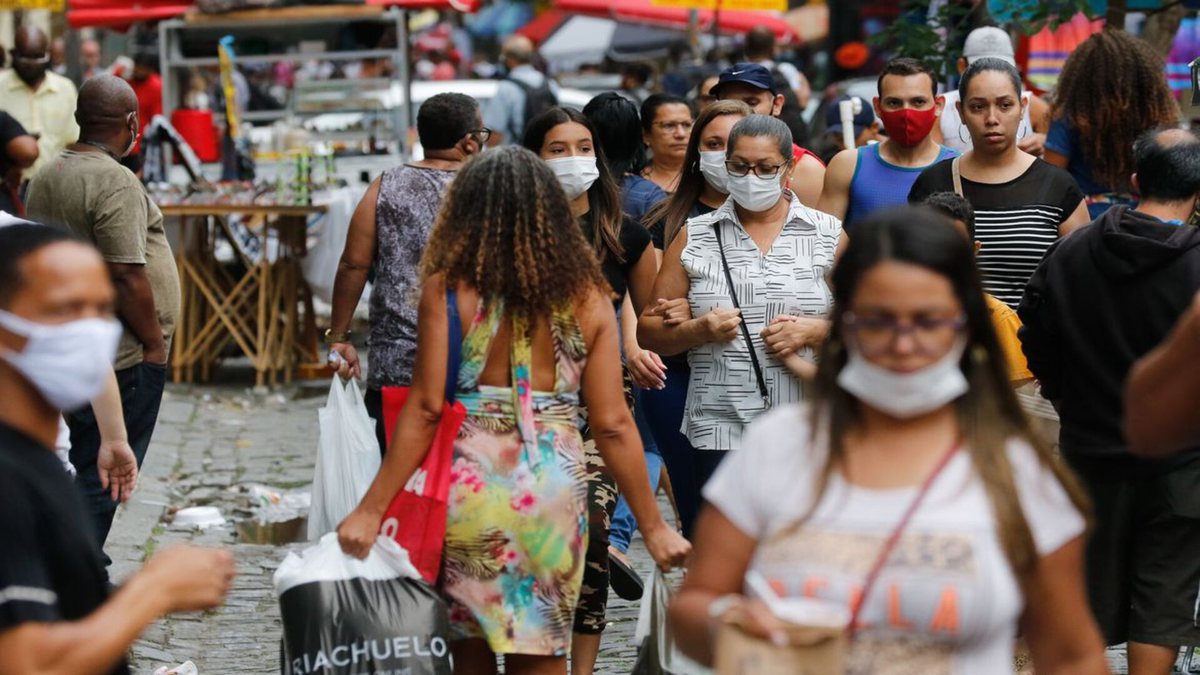 Pessoas caminhando pelas ruas com máscaras