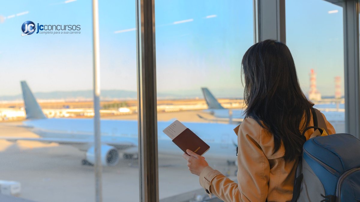 Mulher em aeroporto segura passaporte e olha avião