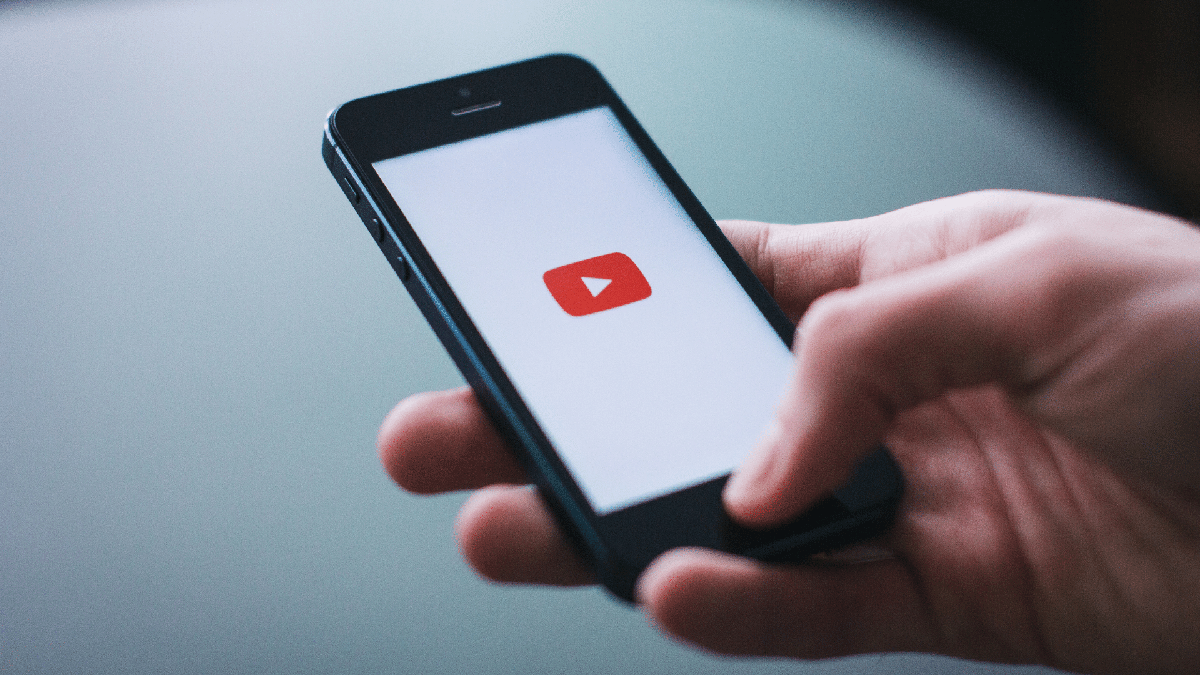Pessoa secura celular com logo do YouTube - Divulgação